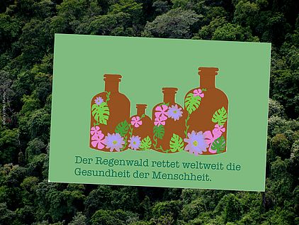 Eine Postkarte zeigt braune Medizinflaschen mit bunten Blüten darauf. Auf der Karte steht: Der Regenwald rettet weltweit die Gesundheit der Menschheit.